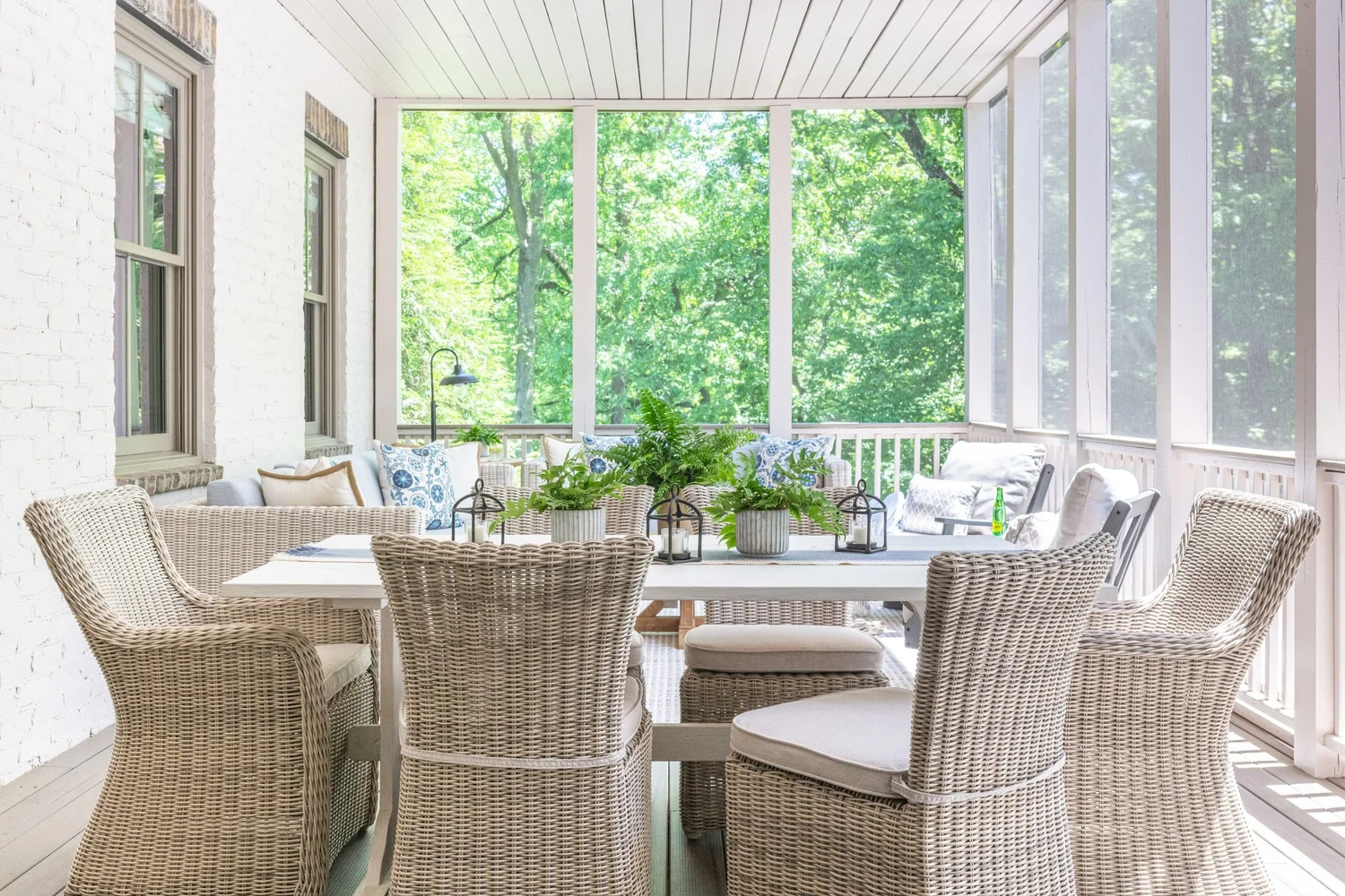 A covered porch with woven seating, an outdoor rug and ceiling fans overhead